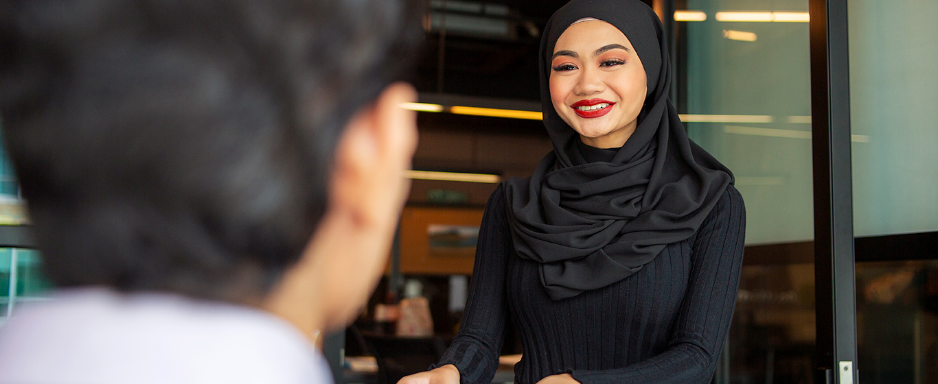 wanita berhijab hitam tersenyum menyapa pria