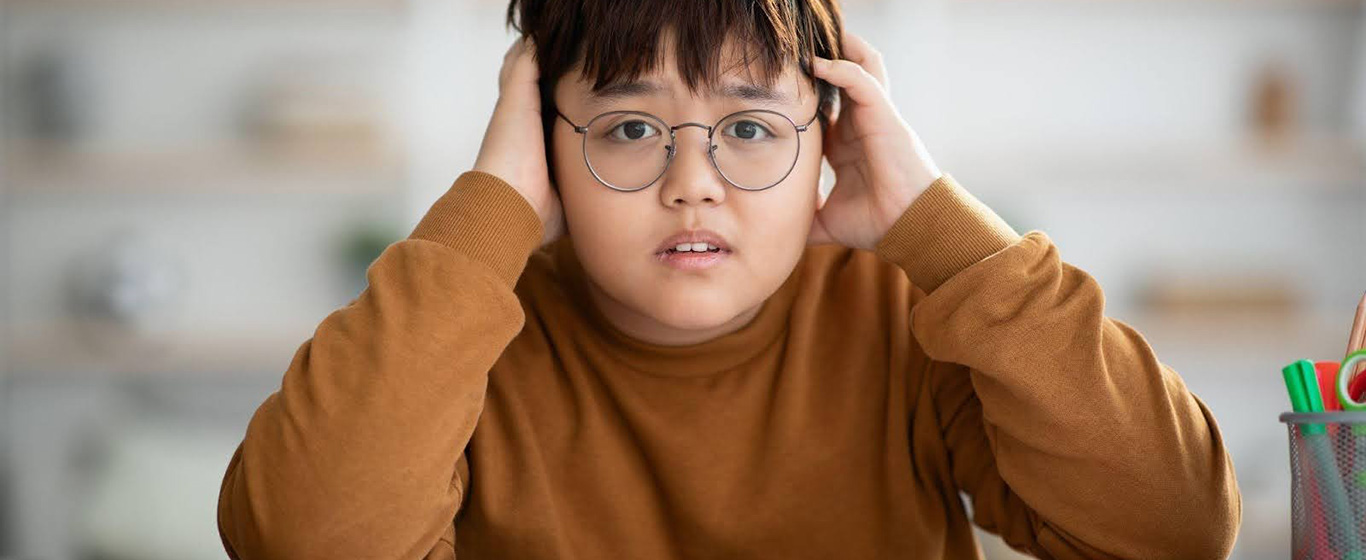 Anak kecil berkacamata memegang kepala