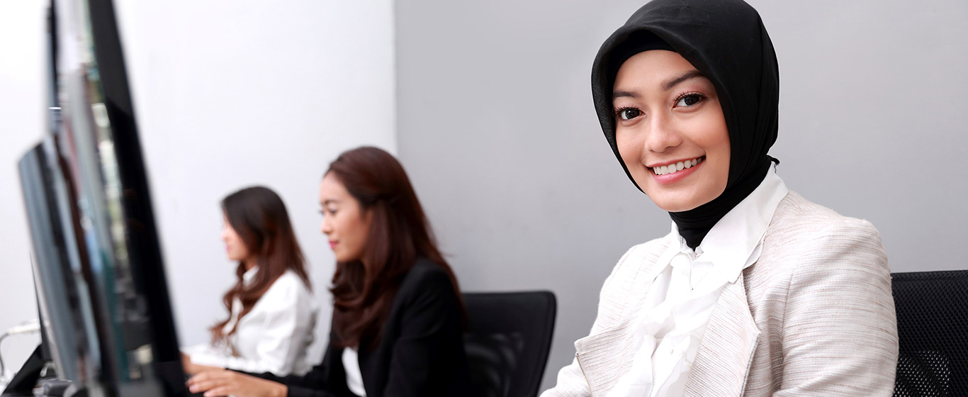 wanita muslim tersenyum di meja kerja