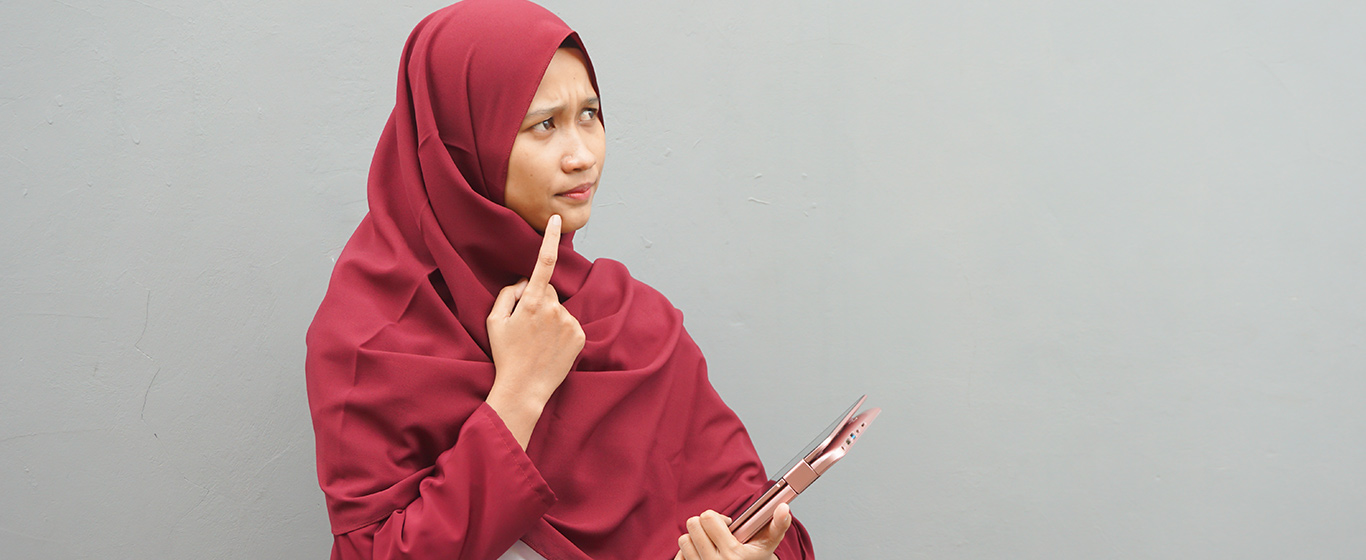 wanita berhijab merah menunjuk dagu dan berpikir